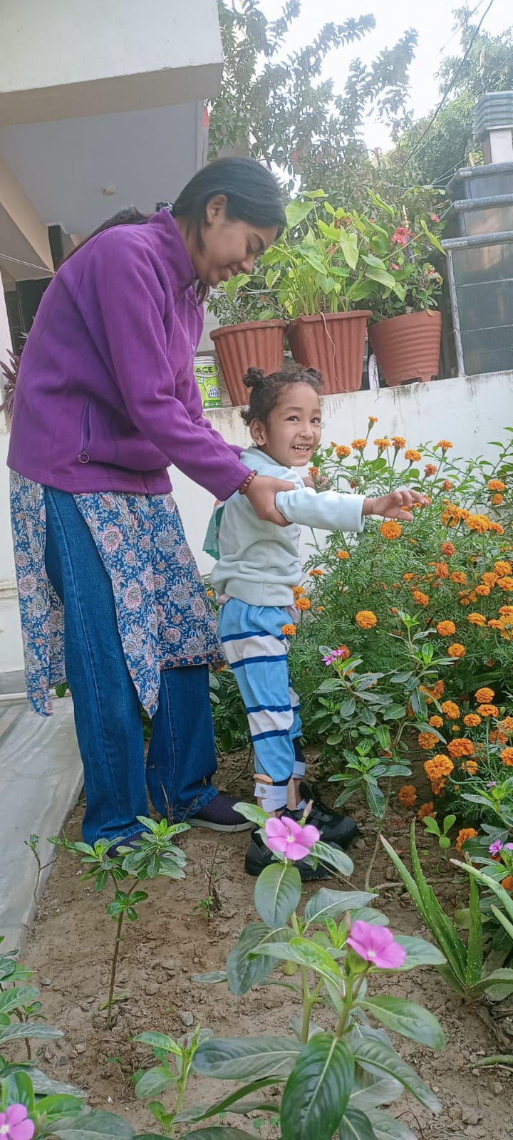 A volunteer helping a child tend marigolds in the society's garden
